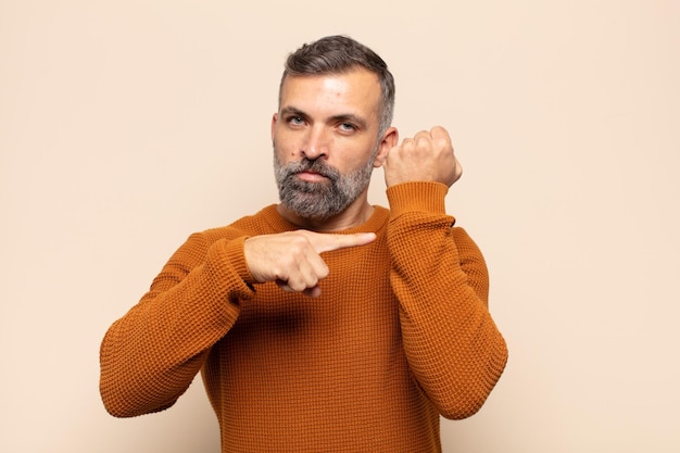 Hombre guapo adulto que parece impaciente y enojado, señalando el reloj, pidiendo puntualidad, quiere llegar a tiempo