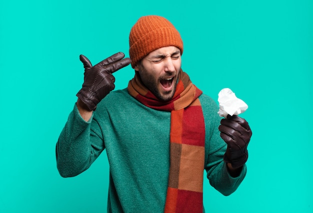 Foto hombre guapo adulto que parece infeliz y estresado, gesto de suicidio haciendo un signo de pistola con la mano, apuntando a la cabeza. enfermedad y concepto de resfriado