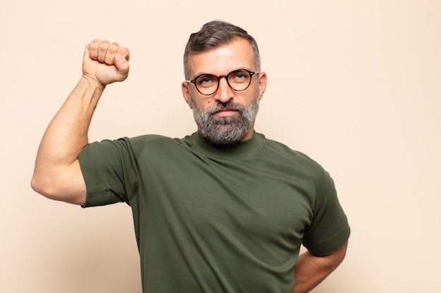 Hombre guapo adulto que se siente serio, fuerte y rebelde, levantando el puño, protestando o luchando por la revolución