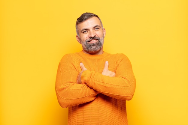 Hombre guapo adulto riendo felizmente con los brazos cruzados, con una pose relajada, positiva y satisfecha