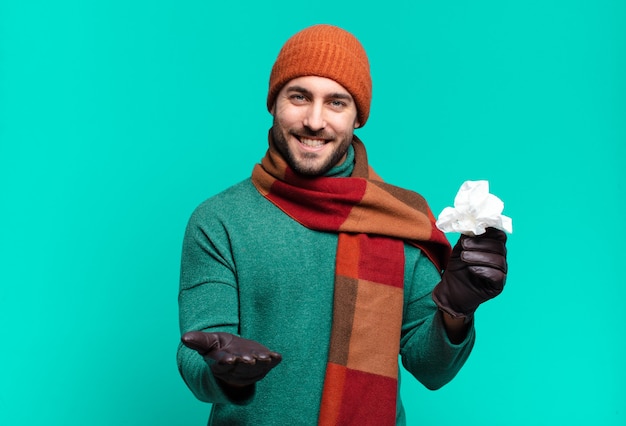 Hombre guapo adulto sonriendo felizmente con mirada amistosa, segura y positiva, ofreciendo y mostrando un objeto o concepto. enfermedad y concepto de resfriado