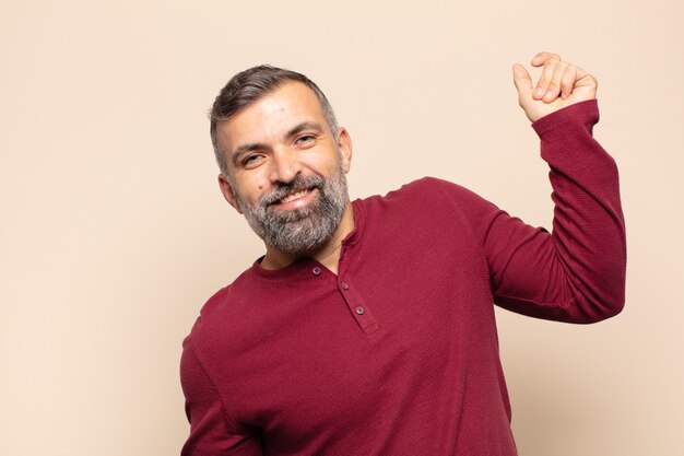 Foto hombre guapo adulto sonriendo, sintiéndose despreocupado, relajado y feliz, bailando y escuchando música, divirtiéndose en una fiesta