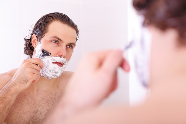 Foto hombre guapo afeitado en el baño.