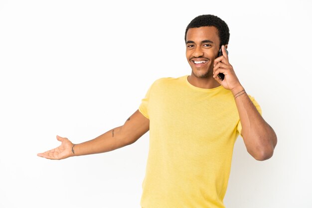 Hombre guapo afroamericano mediante teléfono móvil sobre fondo blanco aislado extendiendo las manos hacia el lado para invitar a venir