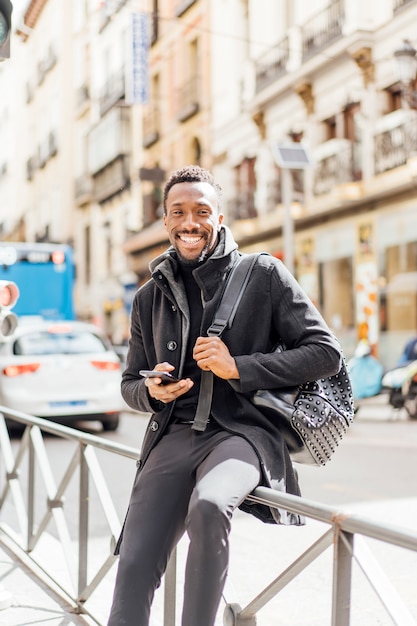 Hombre guapo afroamericano mediante teléfono móvil.