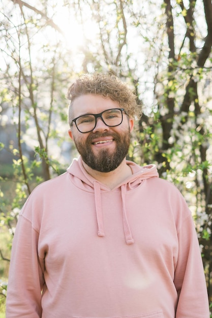 Foto hombre guapo al aire libre retrato en fondo flores de cerezo o flores de manzana generación milenaria