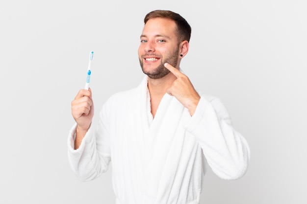 Hombre guapo con albornoz y sosteniendo un cepillo de dientes