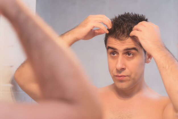 Foto hombre guapo aplicando gel para el cabello