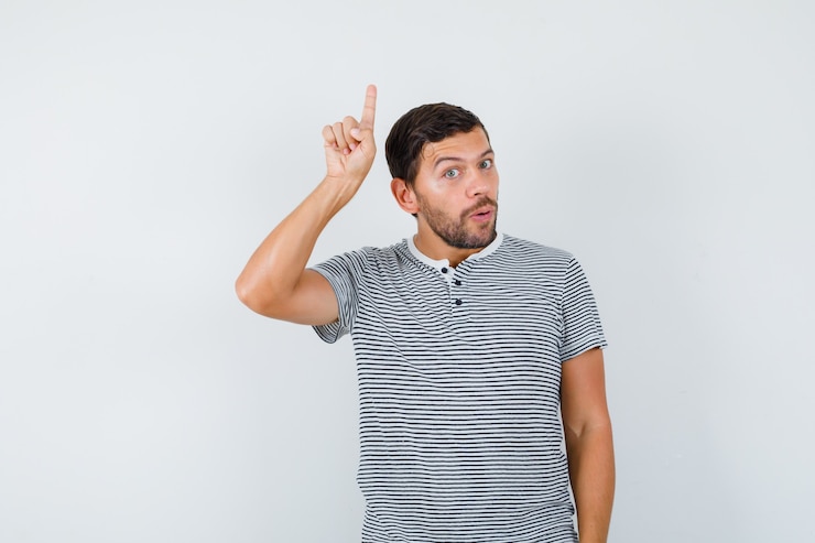 Foto hombre guapo apuntando hacia arriba en camiseta y mirando sorprendido. vista frontal.