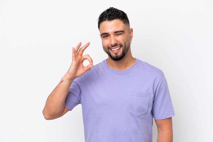 Foto hombre guapo árabe joven aislado sobre fondo blanco que muestra el signo ok con los dedos