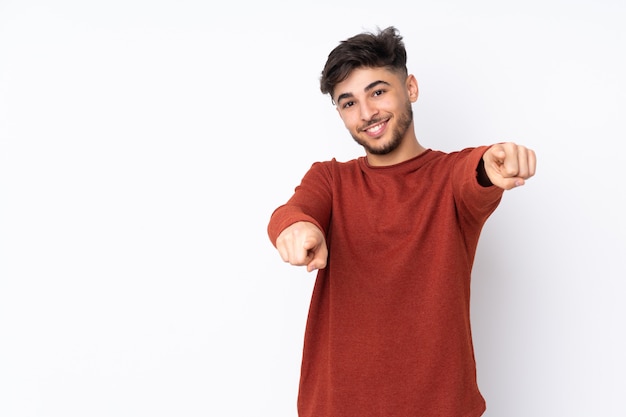 Hombre guapo árabe sobre pared apuntando al frente con expresión feliz