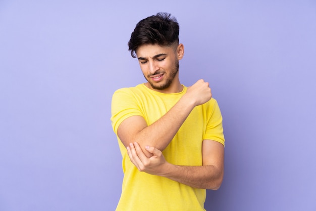 Hombre guapo árabe sobre pared con dolor en el codo