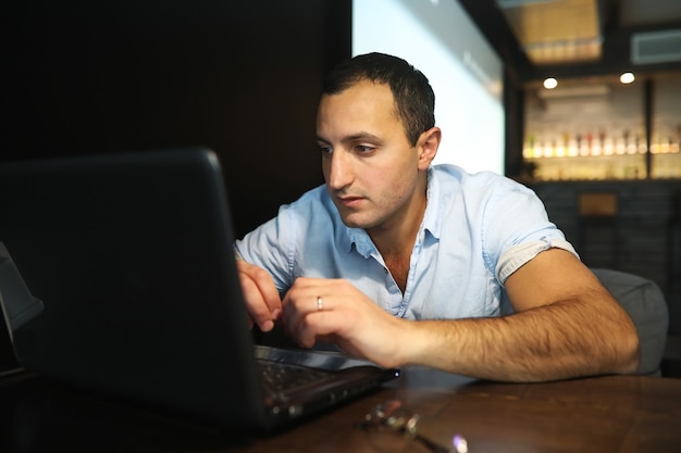 Hombre guapo armenio trabajando detrás de la computadora portátil en el café