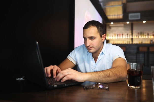 Hombre guapo armenio trabajando detrás de la computadora portátil en el café