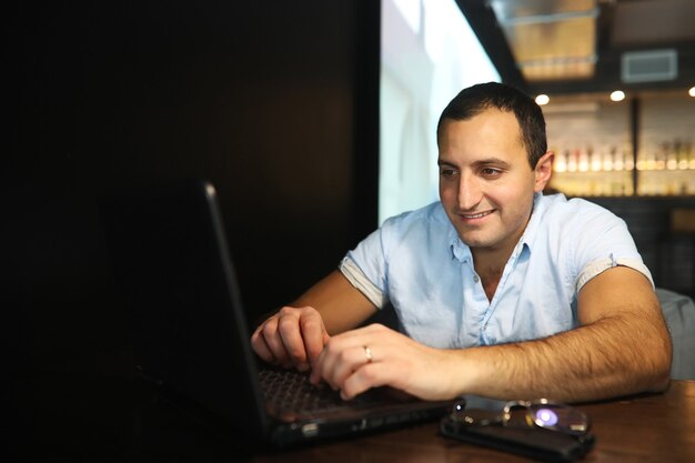 Hombre guapo armenio trabajando detrás de la computadora portátil en el café