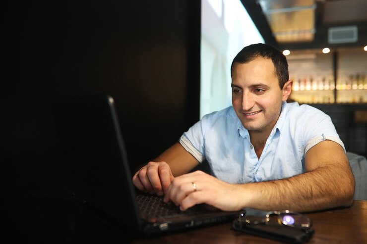 Foto hombre guapo armenio trabajando detrás de la computadora portátil en el café