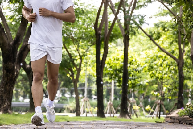 Hombre guapo asiático con camisa blanca corriendo en el parque Concepto de estilo de vida saludable en el parque