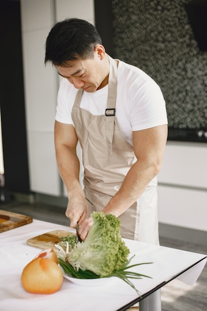 Hombre guapo asiático cocinando en casa.