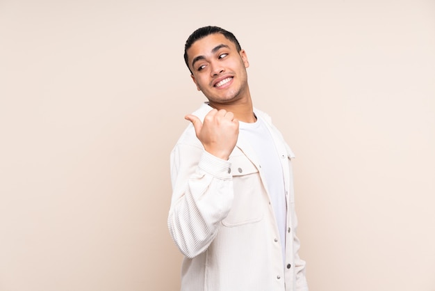 Hombre guapo asiático sobre fondo aislado apuntando hacia el lado para presentar un producto