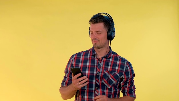 Hombre guapo en auriculares disfrutando de escuchar la música que escucha pistas en el teléfono inteligente