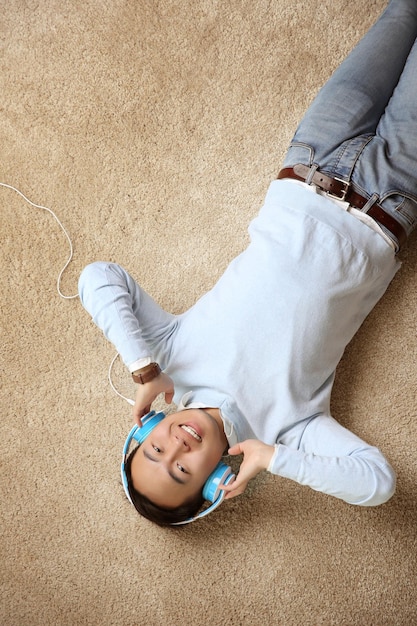 Hombre guapo con auriculares tirados en el suelo