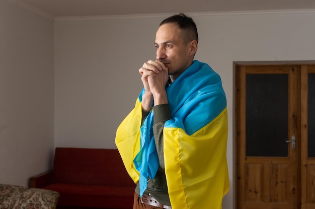 Hombre guapo con bandera de Ucrania en casa.