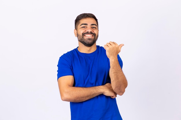 Hombre guapo con barba apunta con el pulgar al espacio libre para texto