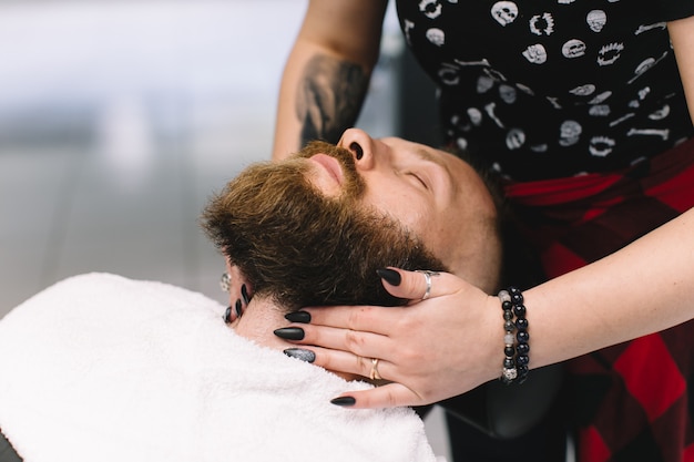 Hombre guapo con barba y bigote afeitado en barbería.