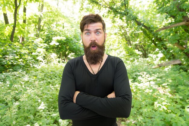 Hombre guapo con barba y bigote en la naturaleza Brutalidad del concepto de selva Temporada de calor de verano Naturaleza salvaje Hombre barbudo hipster fondo de follaje brillante Chico relajarse en el bosque Explorando la naturaleza