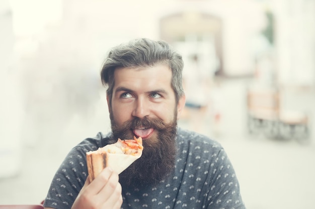 Hombre guapo con barba comiendo pizza