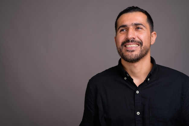 Hombre guapo con barba contra la pared gris