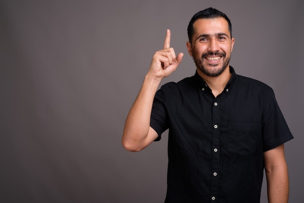 Hombre guapo con barba contra la pared gris