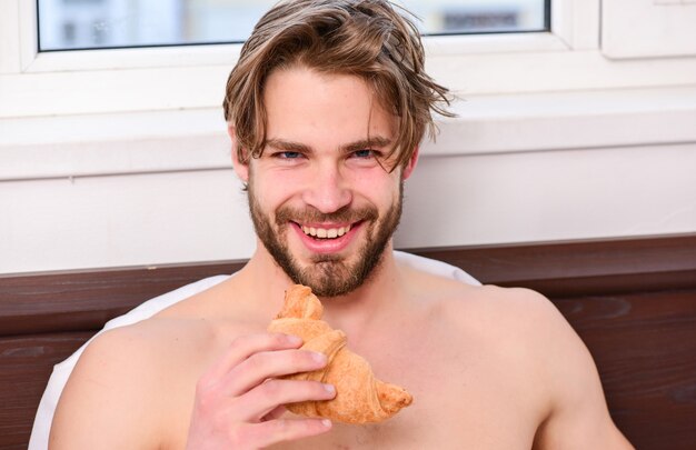 Hombre guapo con barba desayunando en la cama Hombre guapo bebiendo café por la mañana en la cama