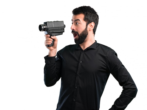 Hombre guapo con barba filmando sobre fondo blanco