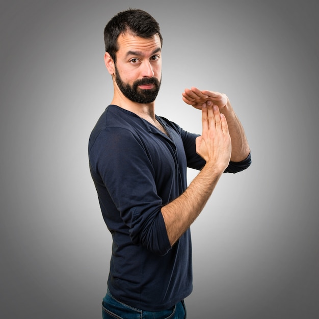 Hombre guapo con barba haciendo tiempo gesto sobre fondo gris