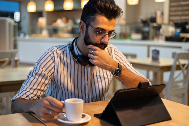 Hombre guapo con barba mirando tableta dentro de una panadería