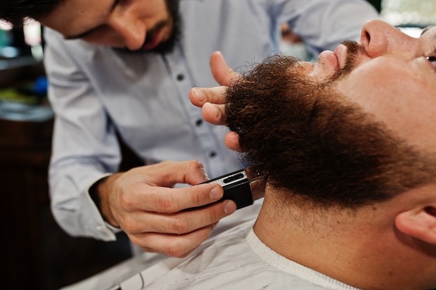 Foto hombre guapo con barba en la peluquería, barbero en el trabajo.