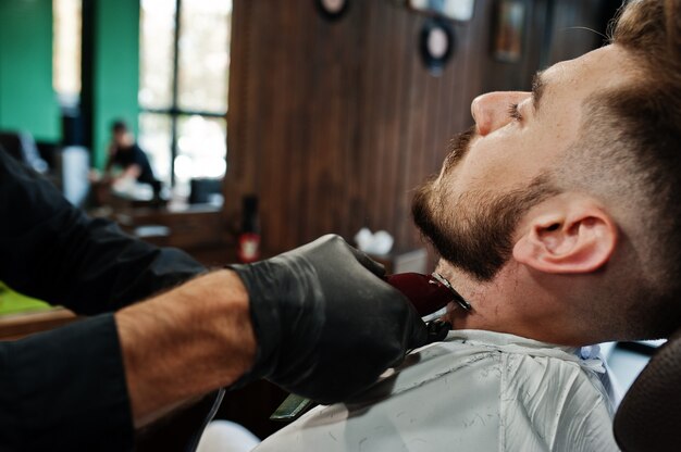 Hombre guapo con barba en la peluquería, barbero en el trabajo.