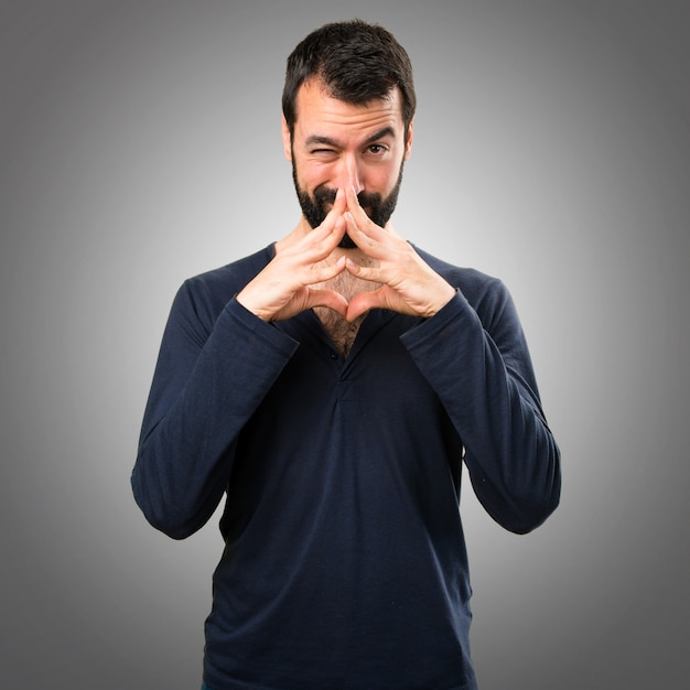 Hombre guapo con barba pensando en fondo gris