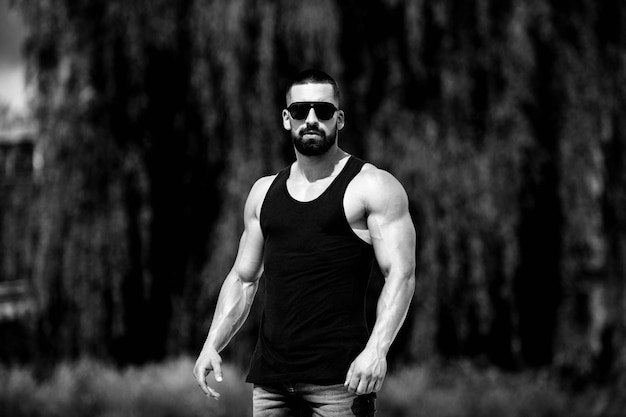 Hombre guapo con barba de pie fuerte y posando al aire libre - Naturaleza de fondo de las hojas