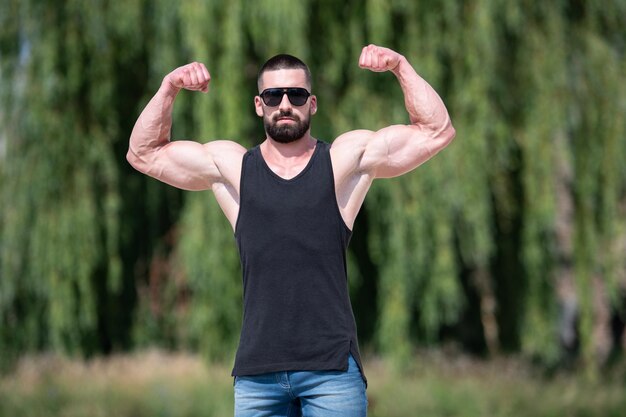 Hombre guapo con barba de pie fuerte y posando al aire libre - Naturaleza de fondo de las hojas