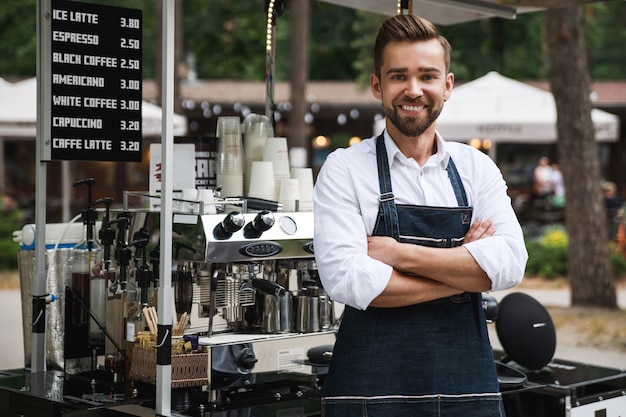 Hombre guapo barista durante el trabajo en su cafetería de la calle móvil