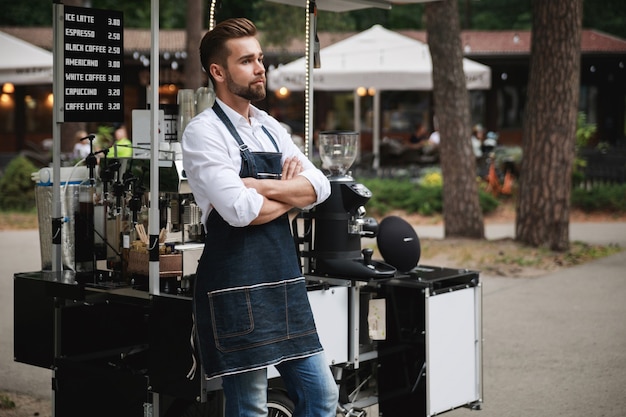 Hombre guapo barista durante el trabajo en su cafetería de la calle móvil