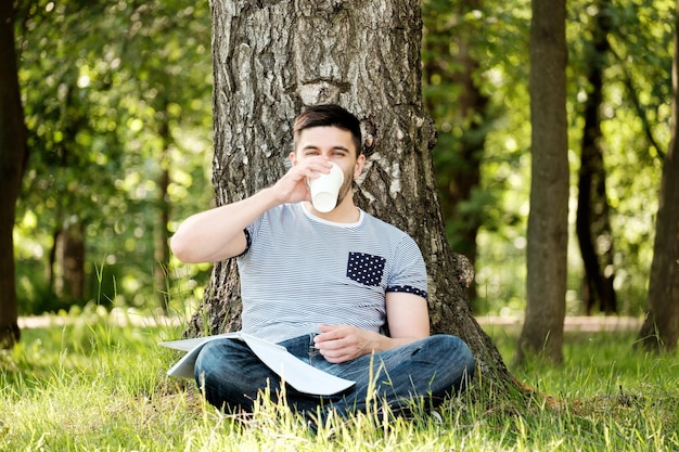 Un hombre guapo bebiendo café en el parque