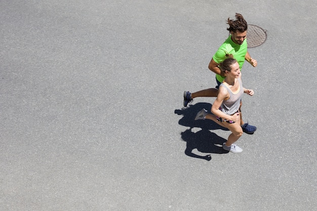 Hombre guapo y bella mujer corriendo juntos en la calle en un día soleado