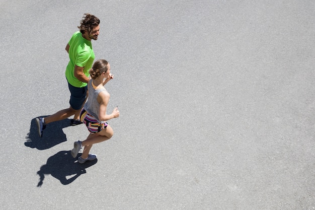 Hombre guapo y bella mujer corriendo juntos en la calle en un día soleado