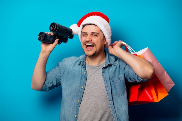 Hombre guapo con binoculares y bolsas de compras