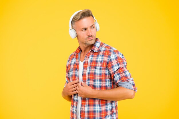 Hombre guapo botón camisa casual escuchando música en auriculares modernos fondo amarillo vida moderna