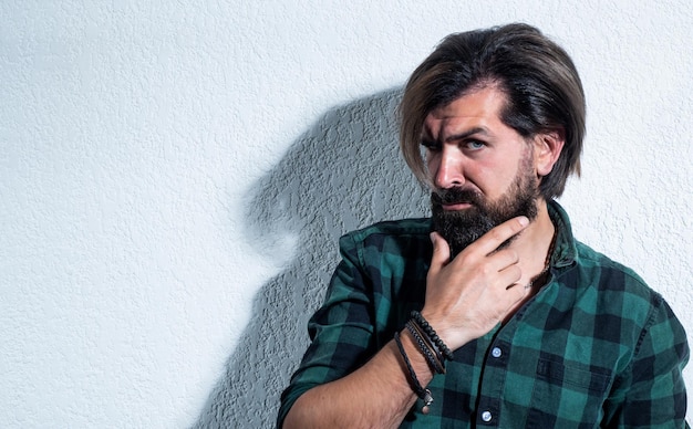 Hombre guapo brutal con bigote y barba con un corte de pelo elegante y usa una camisa a cuadros casual moda masculina y espacio de copia de belleza