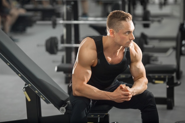 Hombre guapo en buena forma con músculos en el gimnasio